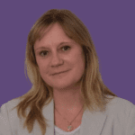 Image of Angie Alderman, smiling at the camera, wearing a beige blazer