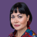 Image of Emma Wee, against a purple background, wearing a colourful shirt