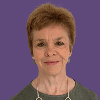 Profile picture of Gill Rudge, smiling at the camera wearing a olive coloured top with a gold necklace on.