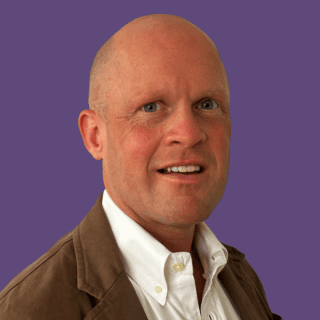 Profile picture of Benjamin Harvey. Looking at camera and smiling, wearing a brown blazer and a white shirt.