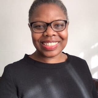 Profile Image of Jacqui Manning, smiling at camera wearing a black top