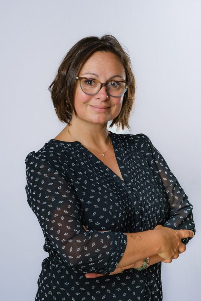 Profile image of Professor Nancy Doyle. She is smiling with arms folded, wearing a black patterned dress.