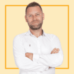 Light yellow background with image of Marc Baker, wearing a white shirt and smiling at the camera.