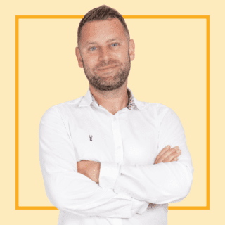 Light yellow background with image of Marc Baker, wearing a white shirt and smiling at the camera.