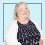 Light blue background with image of Sue Brown, wearing a patterned t-shirt and white cardigan, smiling at the camera.