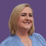 Kelly Bristowm against a purple background, wearing a blue top and smiling at the camera