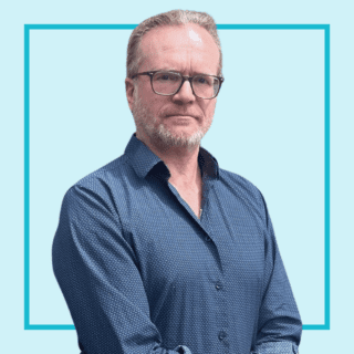 Light blue background with image of Ian McDowall wearing a blue shirt and glasses and smiling at the camera.