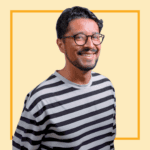 Light yellow background with image of Zaq Mughal wearing a stripey black and white top and glasses, smiling at the camera.