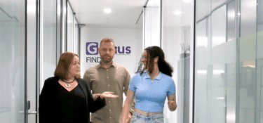 Image of two women and a man walking down an office corridor, with the Genius Finder logo in the background