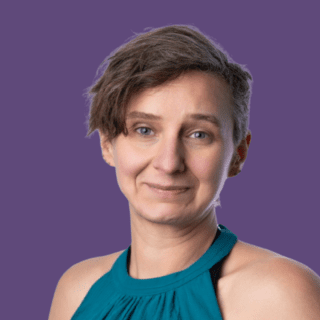 Purple background with image of Vic Brookes, smiling at the camera wearing a teal blouse.